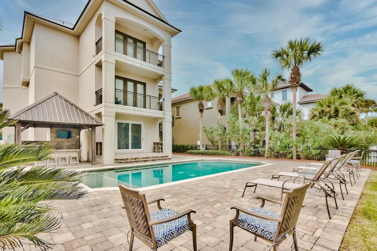 Three-story house with a long pool, lounge chairs and a gazebo